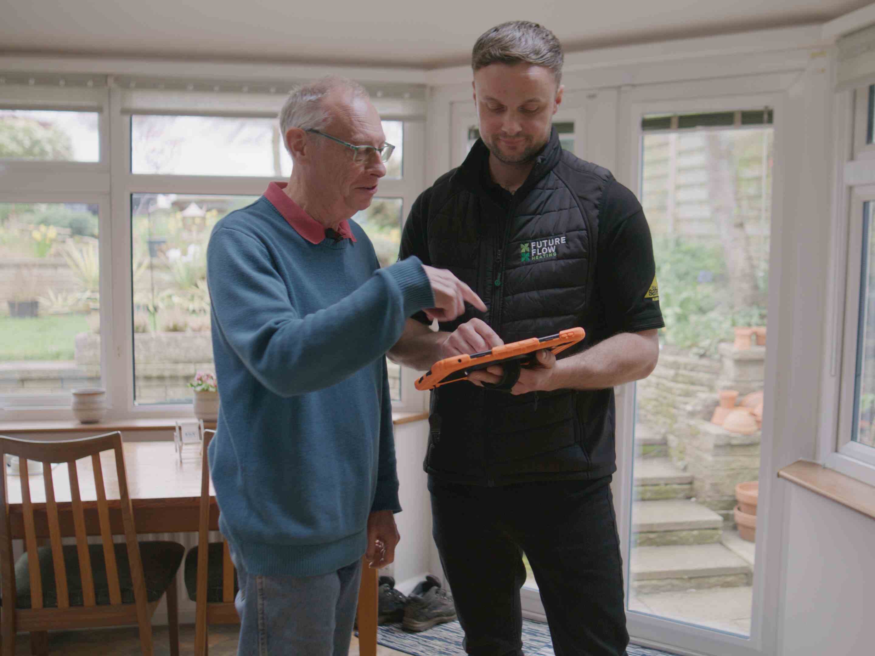 A Heat Geek installer going through a survey on a tablet with a homeowner